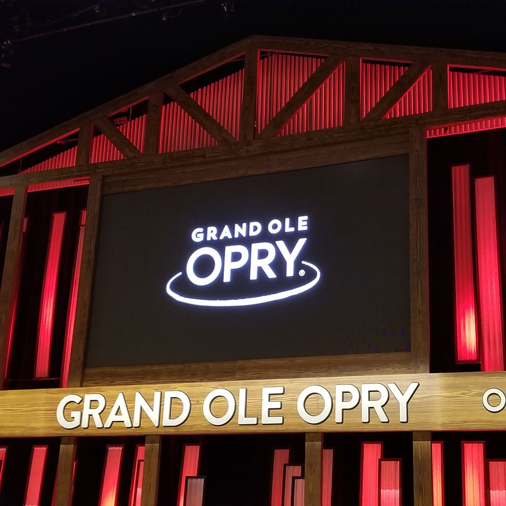 destination nashville 4 the image displays a sign for the grand ole opry, featuring large illuminated letters against a background of red and black paneling.