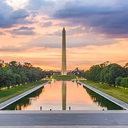 the washington monument reflecting in the lincoln memorial reflecting pool at sunset, surrounded by trees, with a colorful sky and clouds above. the washington monument reflecting in the lincoln memorial reflecting pool at sunset, surrounded by trees, with a colorful sky and clouds above.